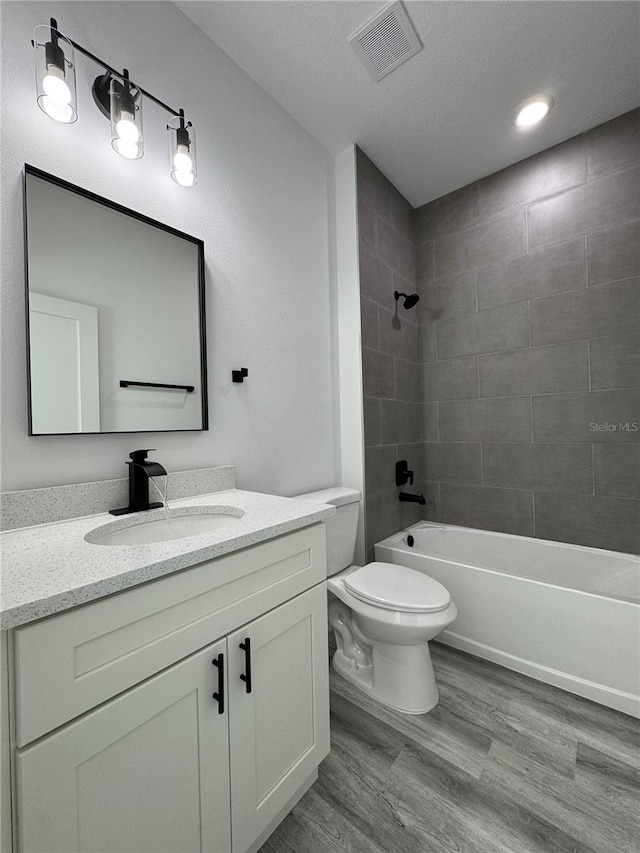 full bathroom with tiled shower / bath, wood-type flooring, toilet, and vanity