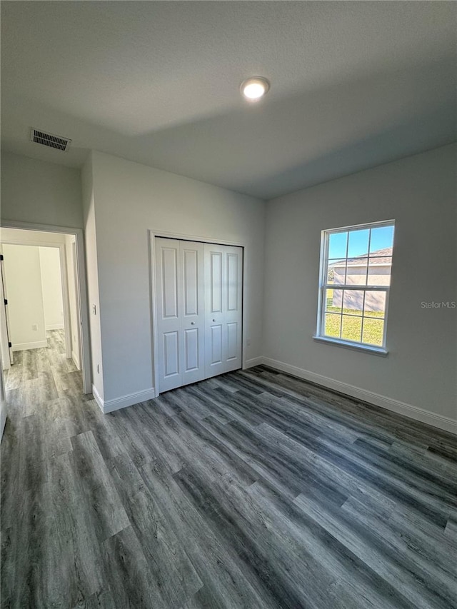 unfurnished bedroom with a closet and dark hardwood / wood-style floors