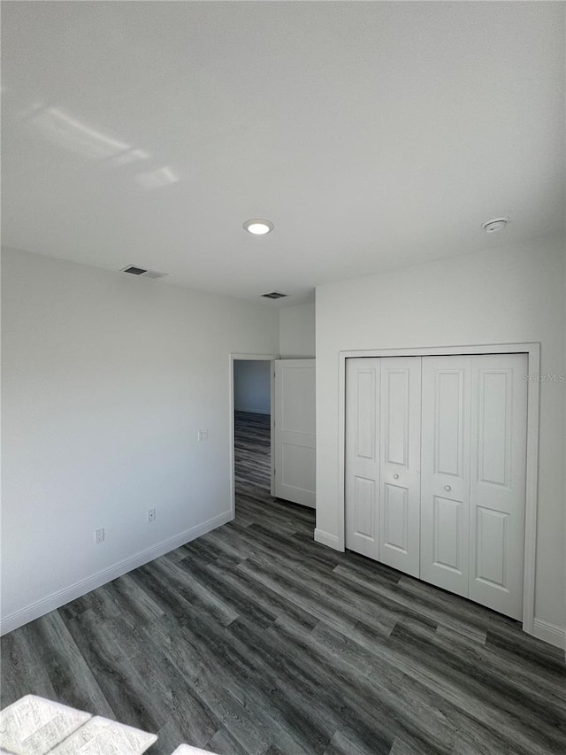 unfurnished bedroom with dark hardwood / wood-style flooring and a closet