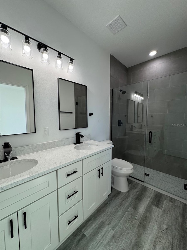 bathroom with vanity, wood-type flooring, toilet, and walk in shower