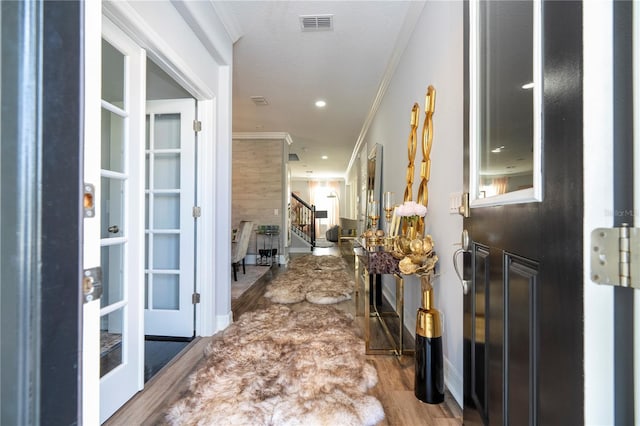 corridor featuring light hardwood / wood-style floors, ornamental molding, and a textured ceiling