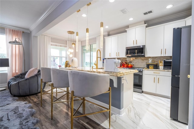 kitchen with a kitchen breakfast bar, appliances with stainless steel finishes, decorative light fixtures, and white cabinetry