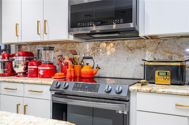 kitchen featuring backsplash, appliances with stainless steel finishes, light stone countertops, and white cabinetry