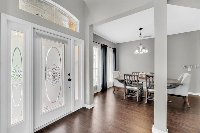 foyer entrance featuring dark wood-type flooring, visible vents, baseboards, and an inviting chandelier