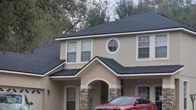 view of front of property with stone siding, a shingled roof, an attached garage, and stucco siding