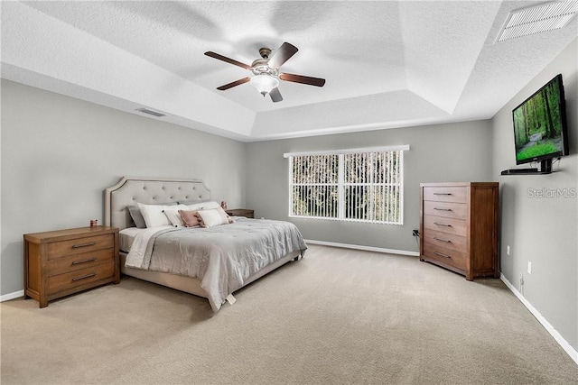 bedroom with light carpet, a tray ceiling, visible vents, and baseboards