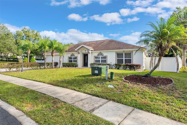 view of front of house featuring an attached garage, fence, a front lawn, and stucco siding