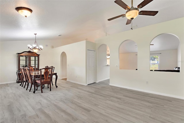 dining room featuring light hardwood / wood-style floors, lofted ceiling, a textured ceiling, and ceiling fan with notable chandelier