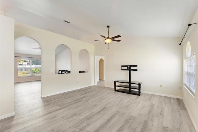 unfurnished living room with ceiling fan, arched walkways, light wood-style flooring, vaulted ceiling, and visible vents