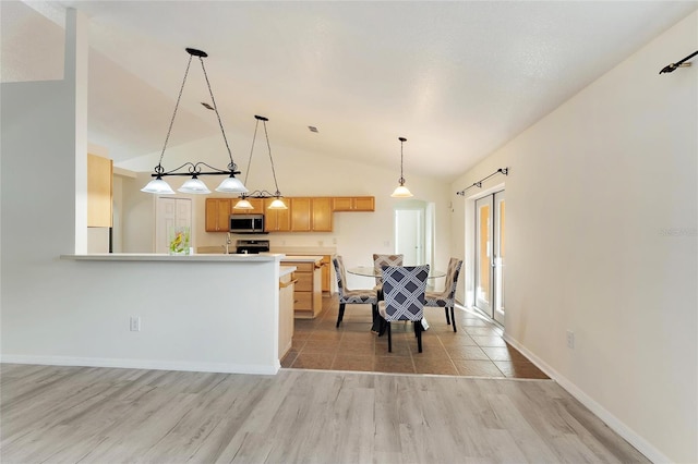 kitchen with appliances with stainless steel finishes, hanging light fixtures, vaulted ceiling, light hardwood / wood-style flooring, and light brown cabinets