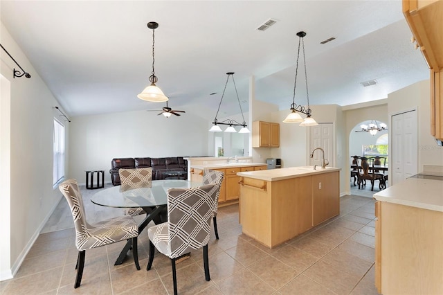 kitchen featuring light brown cabinets, light tile patterned floors, lofted ceiling, and an island with sink