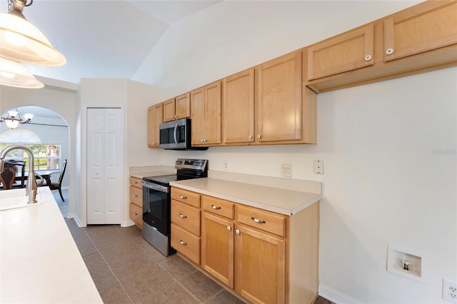 kitchen with dark tile patterned floors, lofted ceiling, hanging light fixtures, a notable chandelier, and appliances with stainless steel finishes