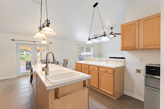 kitchen with light brown cabinets, a kitchen island with sink, sink, and hanging light fixtures