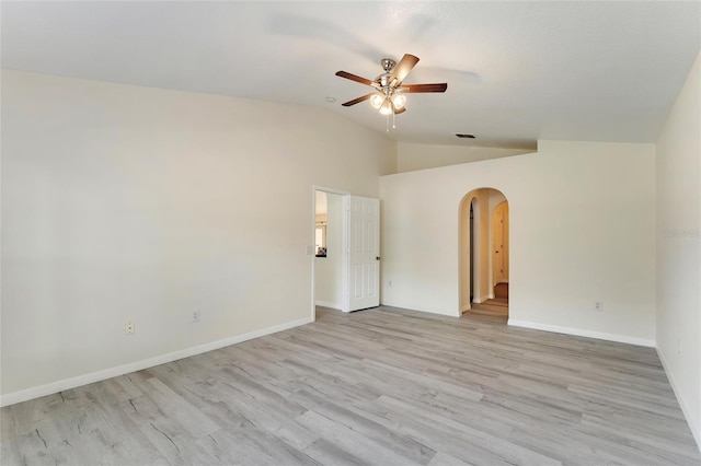 spare room featuring arched walkways, light wood-style flooring, a ceiling fan, baseboards, and lofted ceiling