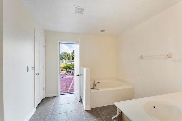 bathroom with a relaxing tiled tub and tile patterned flooring