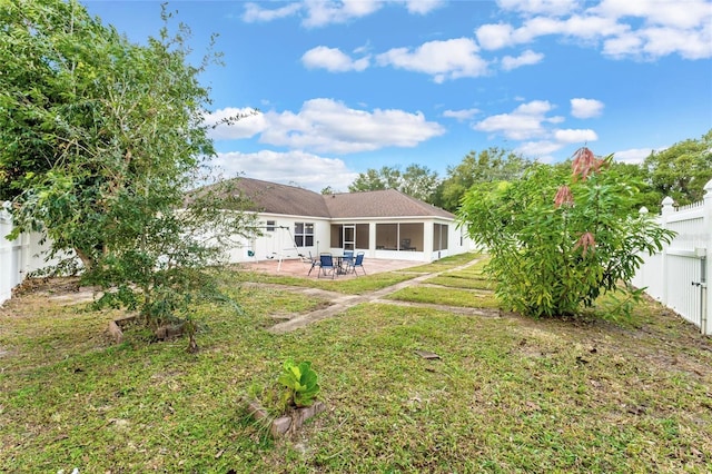 back of property featuring a sunroom, a lawn, a fenced backyard, and a patio area