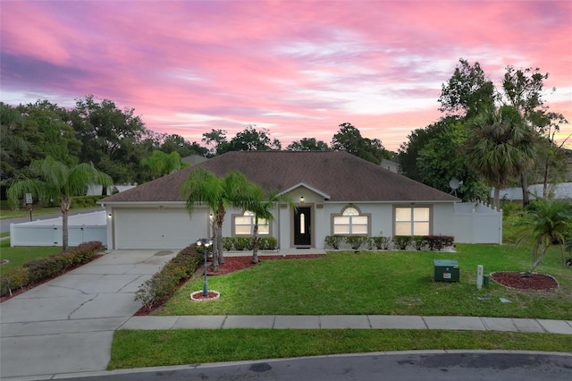 ranch-style house with an attached garage, a front lawn, stucco siding, and driveway