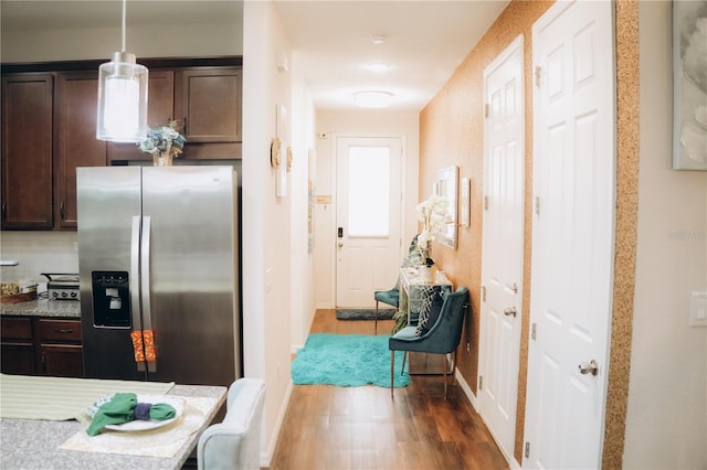 kitchen with backsplash, dark brown cabinets, stainless steel fridge, pendant lighting, and hardwood / wood-style flooring