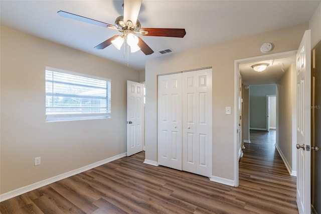 unfurnished bedroom with ceiling fan, dark hardwood / wood-style floors, and a closet