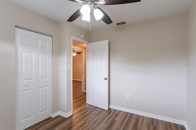 unfurnished bedroom with ceiling fan, dark hardwood / wood-style floors, and a closet