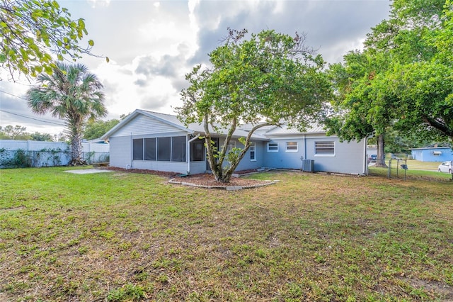 back of house featuring a sunroom, a yard, and central AC