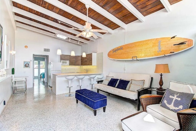 living room featuring a high ceiling, beamed ceiling, wooden ceiling, sink, and ceiling fan