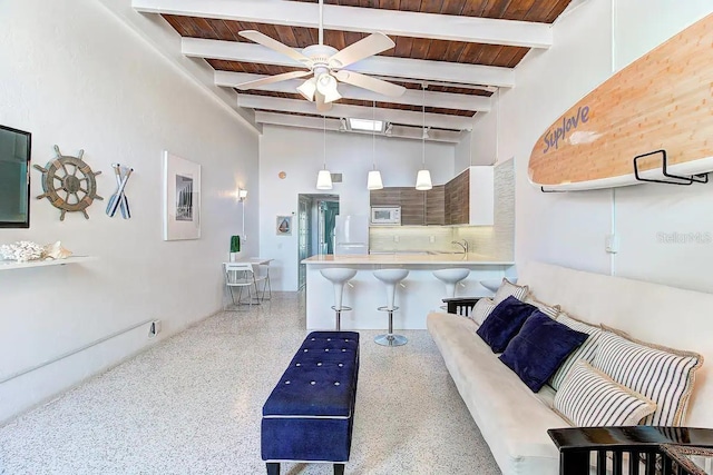 living area with beam ceiling, a towering ceiling, a ceiling fan, wooden ceiling, and speckled floor