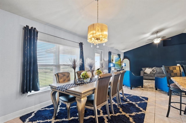 tiled dining space with lofted ceiling and ceiling fan with notable chandelier