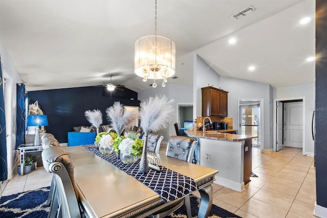 tiled dining space featuring sink, ceiling fan with notable chandelier, and vaulted ceiling