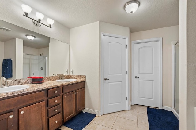 bathroom featuring vanity, walk in shower, a textured ceiling, and tile patterned flooring