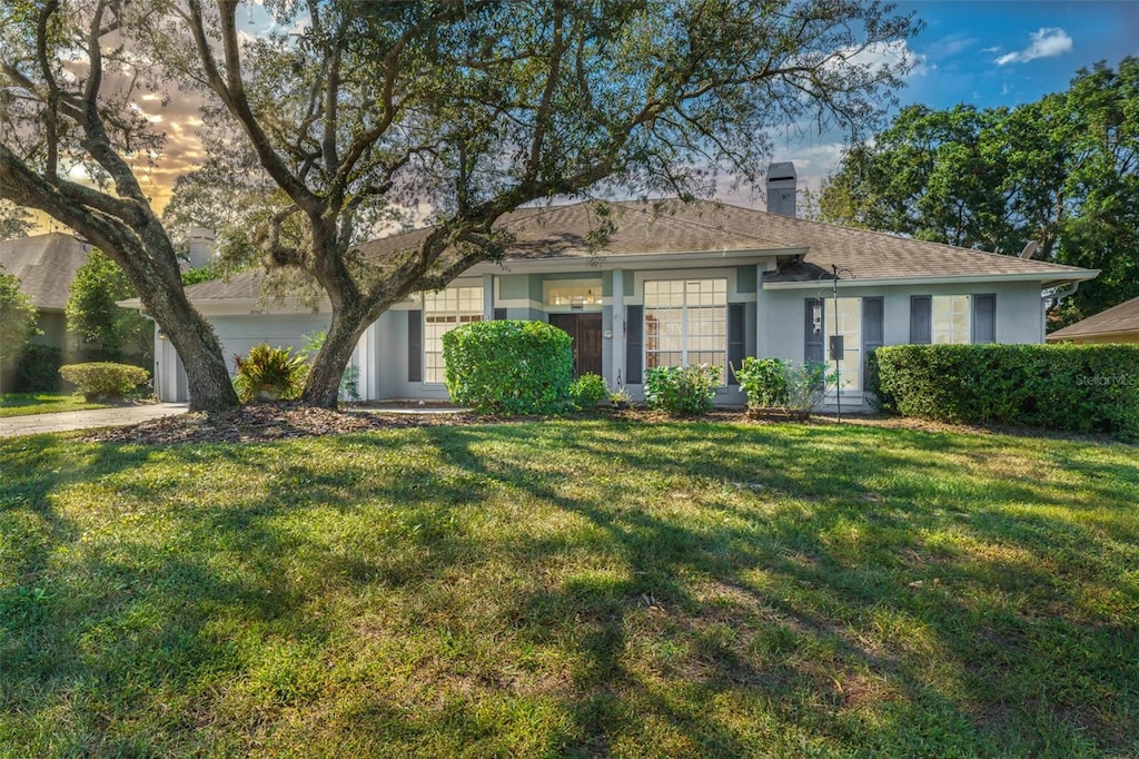 single story home featuring a garage and a front lawn