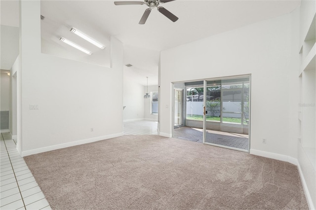 spare room with light carpet, a towering ceiling, and ceiling fan