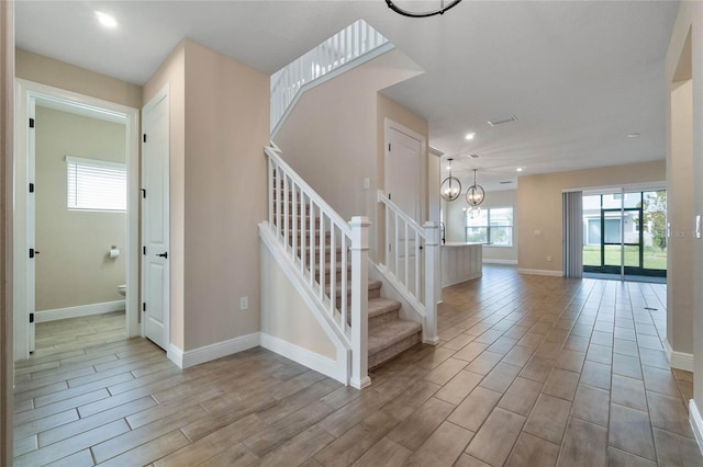 stairway with hardwood / wood-style floors and an inviting chandelier