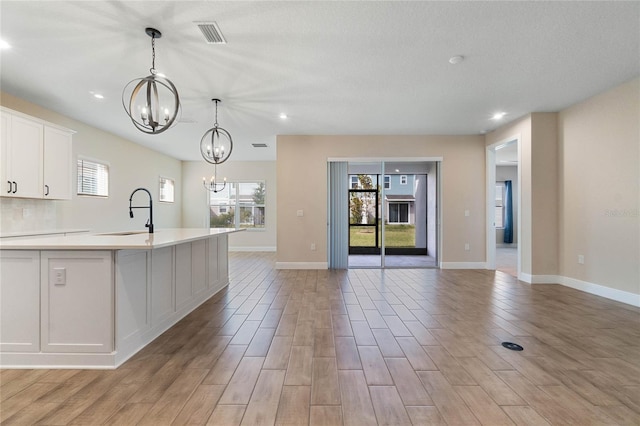 kitchen featuring light wood-type flooring, white cabinetry, plenty of natural light, and sink