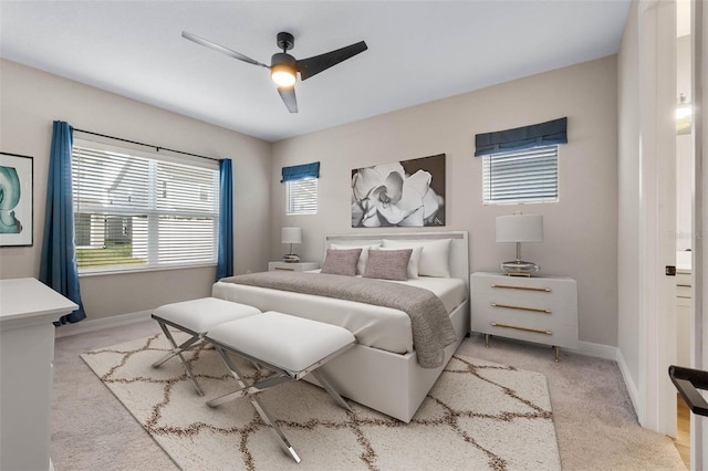 bedroom with ceiling fan, light colored carpet, and multiple windows