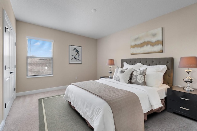 bedroom featuring light carpet, baseboards, and a textured ceiling