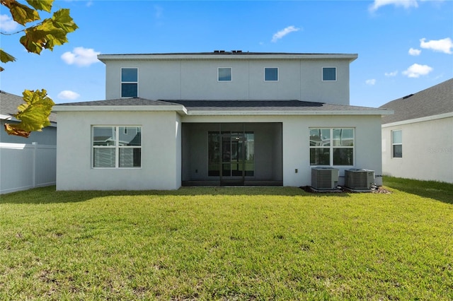 rear view of house with a lawn, stucco siding, cooling unit, and fence