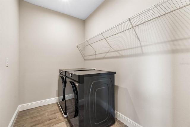 laundry area featuring separate washer and dryer and light hardwood / wood-style flooring