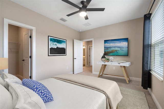 bedroom featuring light carpet, a walk in closet, a closet, and ceiling fan