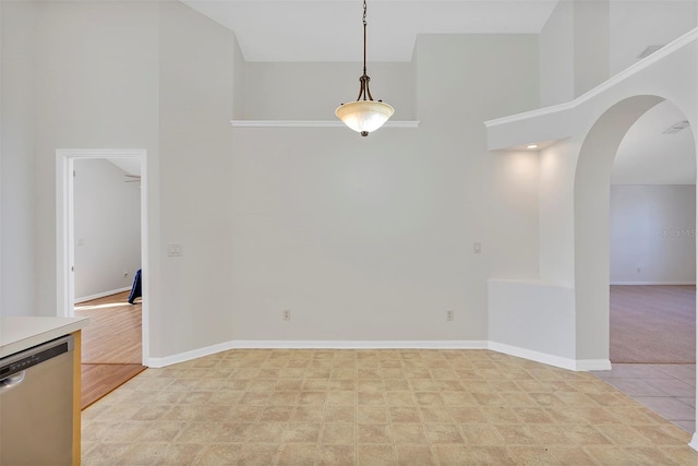 unfurnished dining area with light carpet and a towering ceiling