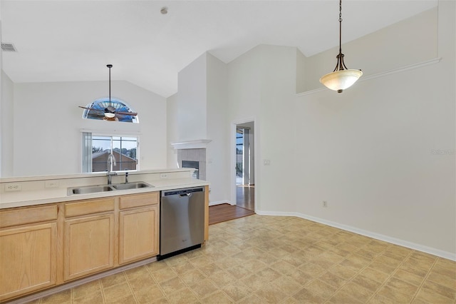 kitchen with light brown cabinets, a tiled fireplace, hanging light fixtures, dishwasher, and sink