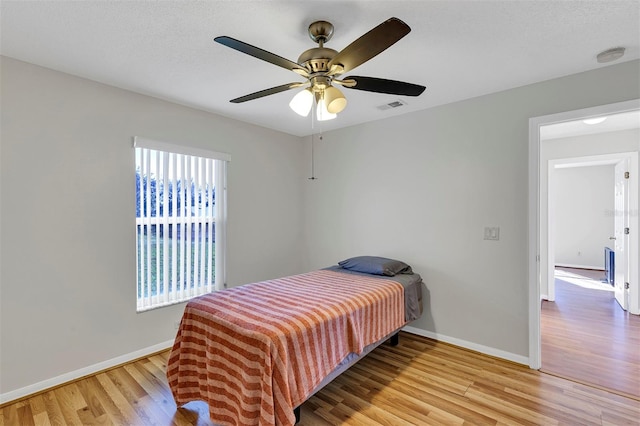 bedroom featuring ceiling fan, a textured ceiling, and light hardwood / wood-style flooring