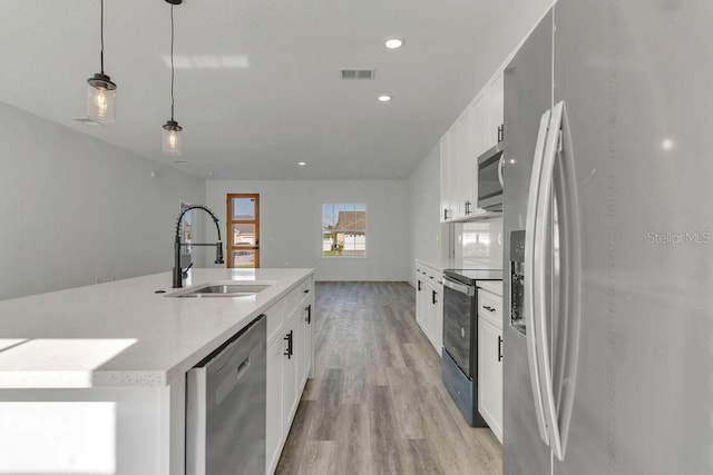 kitchen featuring white cabinets, light hardwood / wood-style flooring, stainless steel appliances, sink, and decorative light fixtures