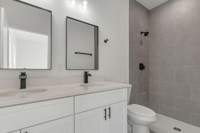 bathroom featuring toilet, vanity, and a tile shower