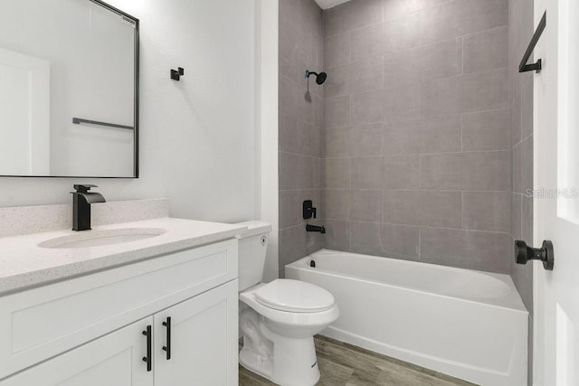 full bathroom with tiled shower / bath, vanity, hardwood / wood-style flooring, and toilet