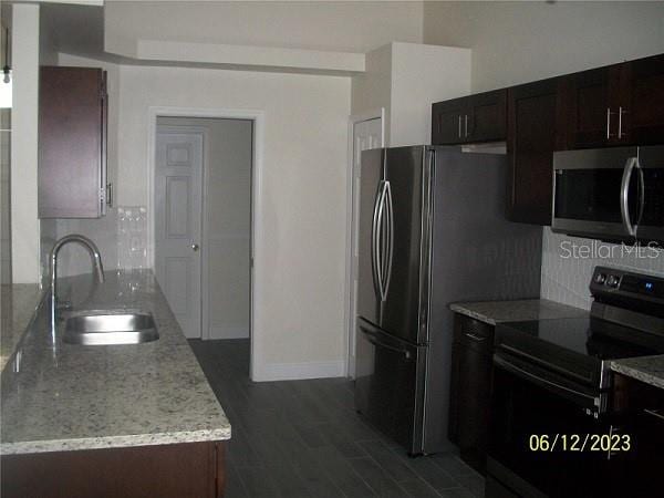 kitchen featuring dark hardwood / wood-style flooring, sink, tasteful backsplash, electric range oven, and light stone countertops