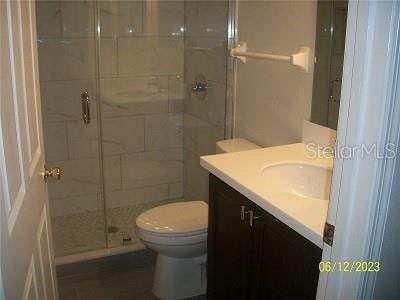 bathroom featuring walk in shower, vanity, and toilet