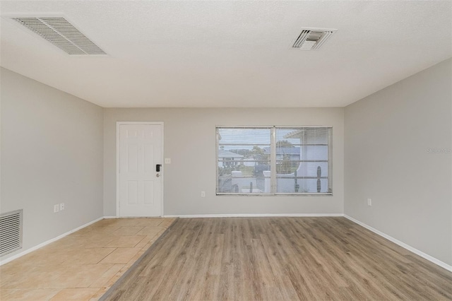 spare room featuring a textured ceiling and light wood-type flooring