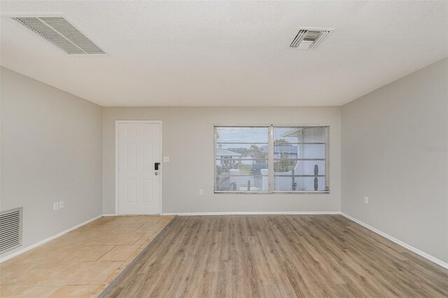 empty room featuring visible vents, light wood-style flooring, and baseboards