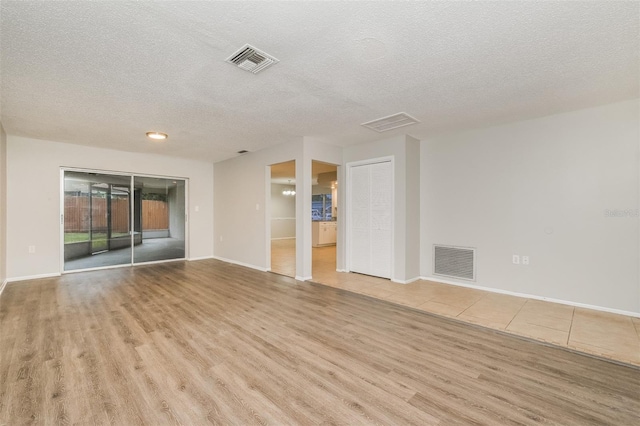 unfurnished room featuring baseboards, visible vents, wood finished floors, and a textured ceiling